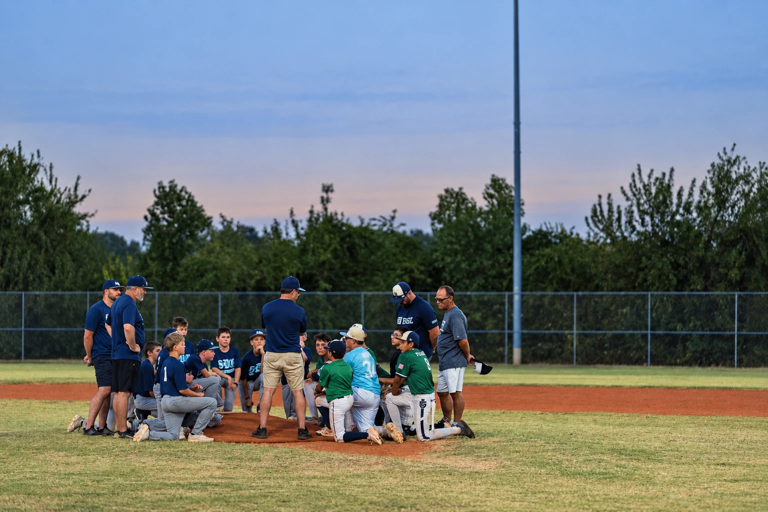 Players and coaches gathered on the baseball field at dusk